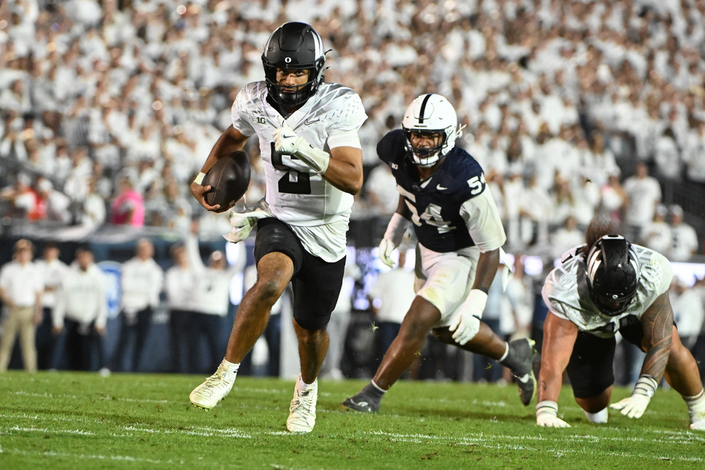 Oregon quarterback Dante Moore (5) runs away from Penn State defensive tackle Xavier Gilliam (54) during the fourth quarter of their NCAA college football game, Saturday, Sept. 27, 2025, in State College, Pa. (AP Photo/Barry Reeger)