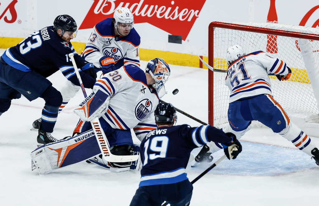 Edmonton Oilers' Riley Stillman (61) clears the loose puck from behind goaltender Calvin Pickard (30) as Winnipeg Jets' Gabriel Vilardi (13) moves in during second period NHL action in Winnipeg, Manitoba, Thursday, Jan. 8, 2026. (John Woods/The Canadian Press via AP)