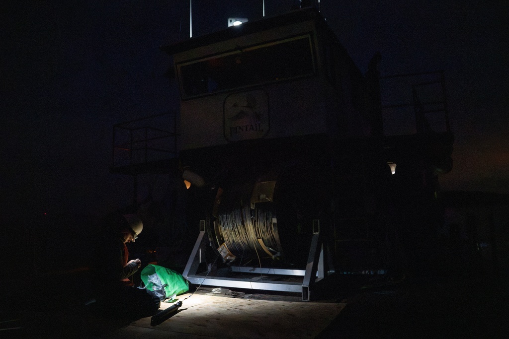 Sam Juber, a graduate student at the University of Washington School of Oceanography, prepares to deploy a 1.3-mile fiber-optic cable to test whether internet cables can detect endangered orca vocalizations near San Juan Island, Wash., Friday, Oct. 10, 2025. (AP Photo/Annika Hammerschlag)