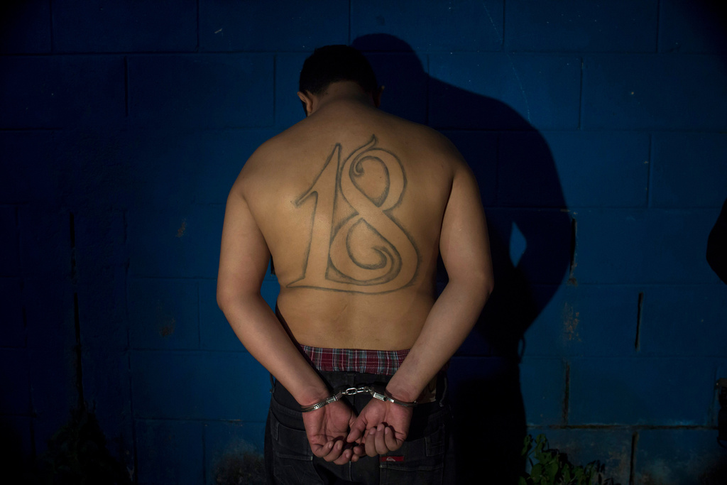 FILE - A leader of the Barrio 18 gang stands handcuffed facing a wall after his arrest in San Salvador, El Salvador, July 28, 2015. (AP Photo/Salvador Melendez, File)