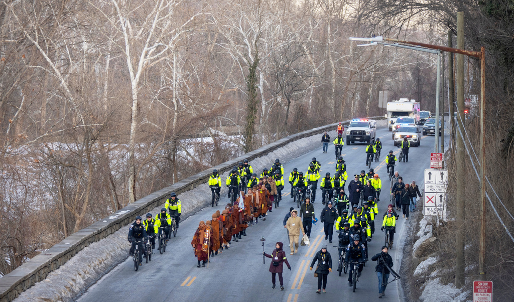 Buddhist monks who are participating in a Walk For Peace are escorted by Metropolitan Police Department officers as they walk along the C&O Canal and Potomac River on Tuesday, Feb. 10, 2026, in Washington. (AP Photo/Mark Schiefelbein)