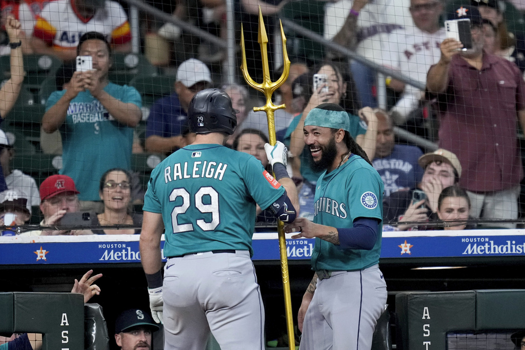 Seattle Mariners' J.P. Crawford, right, presents Cal Raleigh a trident after Raleigh hit a two-run home run against the Houston Astros during the second inning of a baseball game Sunday, Sept. 21, 2025, in Houston. (AP Photo/Eric Christian Smith)
