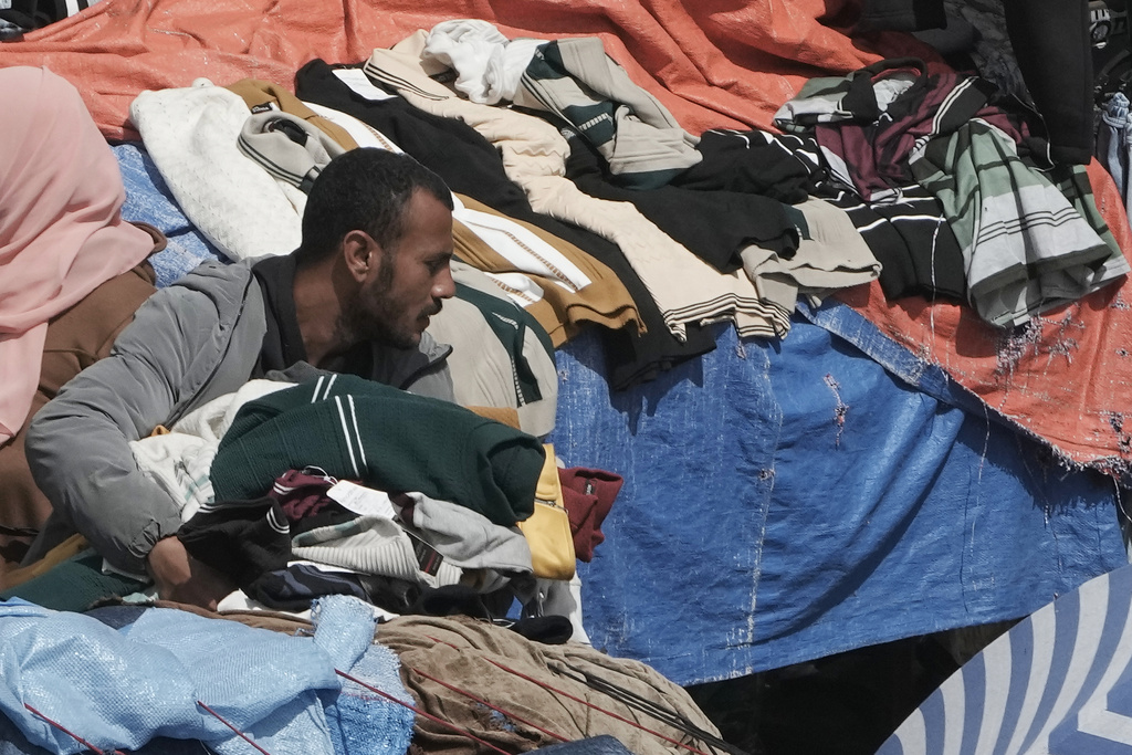 A vendor carries second hand clothes at a popular market in Cairo, Egypt, Tuesday, March 12, 2026. (AP Photo/Amr Nabil)