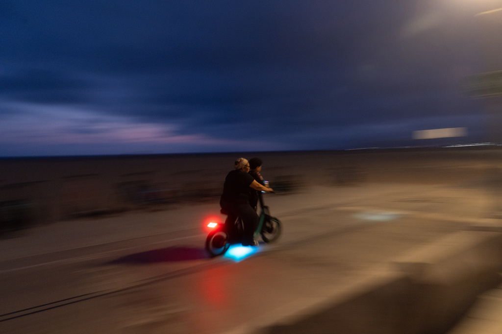 An adult rides an e-bike with a child in Santa Monica, Calif., Monday, Aug. 10, 2026. (AP Photo/Jae C. Hong)