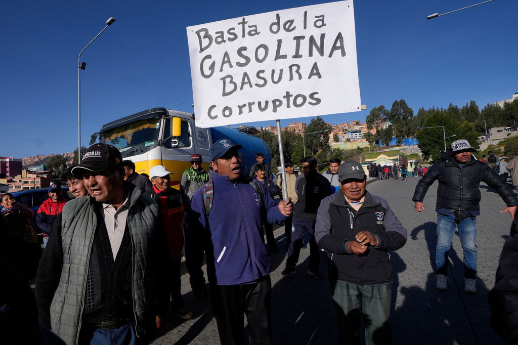 FILE - Public transport drivers protest poor gasoline fuel quality, one holding a sign with a message that reads in Spanish; "Enough with the trash gas. Corrupt ones," in La Paz, Bolivia, March 25, 2026. (AP Photo/Juan Karita, File)