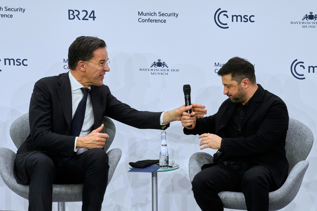 NATO Secretary General Mark Rutte, left, hands Ukraine's President Volodymyr Zelenskyy a microphone during a panel discussion at the Munich Security Conference in Munich, Germany, Saturday, Feb. 14, 2026. (AP Photo/Michael Probst)