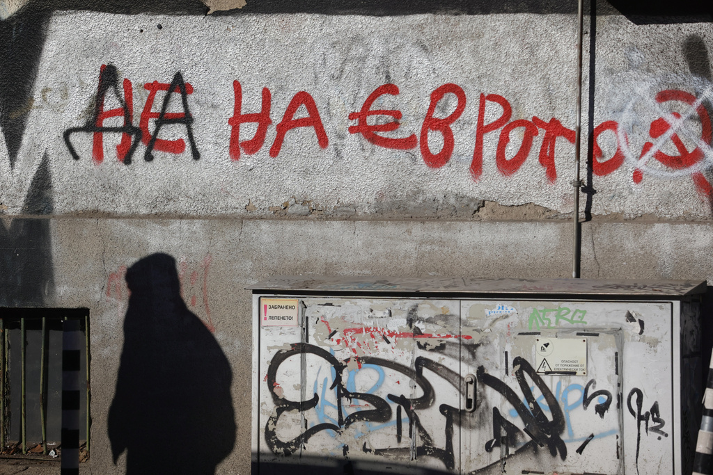 The shadow of a person seen next to graffiti reading "No to the euro" altered to "Yes to the euro" in Sofia, Monday, Dec. 29, 2025. (AP Photo/Valentina Petrova)