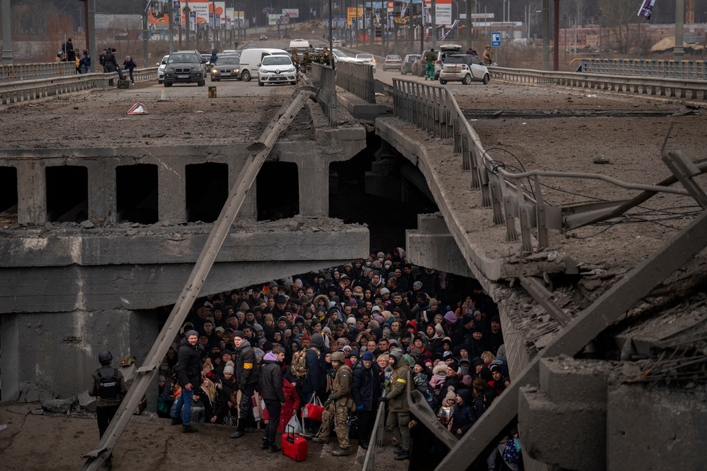 FILE - Ukrainians crowd under a destroyed bridge as they try to flee by crossing the Irpin River on the outskirts of Kyiv, Ukraine, Saturday, March 5, 2022. (AP Photo/Emilio Morenatti, File)