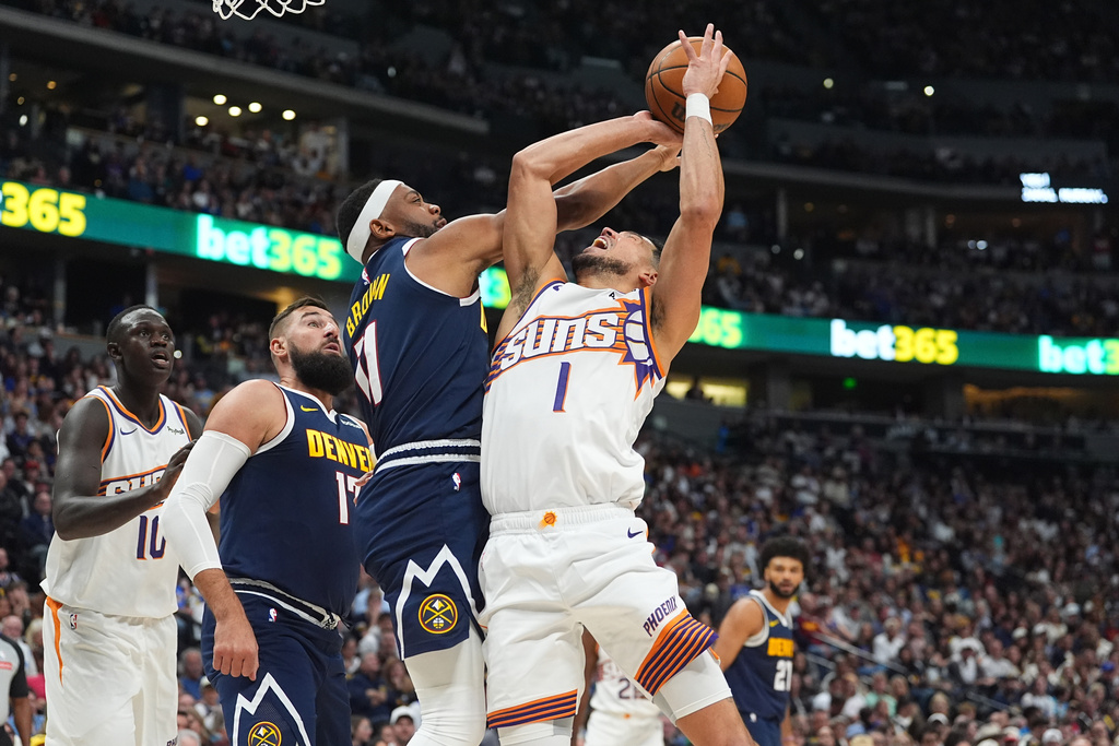 Denver Nuggets guard Bruce Brown, second from front right, fouls Phoenix Suns guard Devin Booker (1) who was driving to the basket in the first half of an NBA basketball game Saturday, Oct. 25, 2025, in Denver. (AP Photo/David Zalubowski)