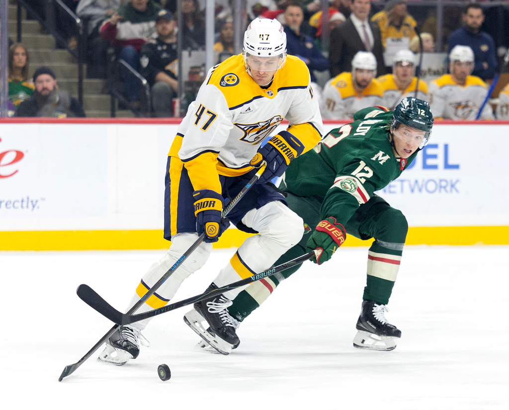 Nashville Predators' Michael McCarron (47) and Minnesota Wild's Matt Boldy (12) battle for the puck in the first period of an NHL hockey game against the Minnesota Wild, Tuesday, Dec. 23, 2025, in St. Paul, Minn. (Carlos Gonzalez/Star Tribune via AP)