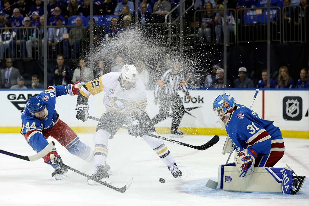 Pittsburgh Penguins defenseman Caleb Jones, center, battles for the puck in between New York Rangers defenseman Vladislav Gavrikov (44) and goaltender Igor Shesterkin (31) in the first period of an NHL hockey game, Tuesday, Oct. 7, 2025, in New York. (AP Photo/Adam Hunger)