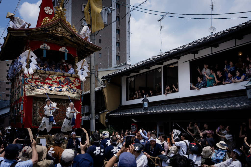 A giant festival float is paraded through a cheering crowd during one of the main parades of Shinto's Gion Matsuri festival in Kyoto, western Japan, Friday, July 17, 2026. (AP Photo/Fred Mery)