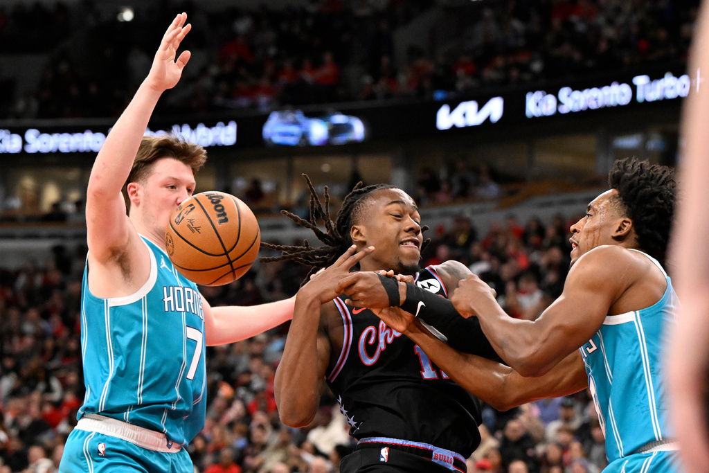 Chicago Bulls guard Ayo Dosunmu, center, loses the ball to Charlotte Hornets guard Kon Knueppel (7) and guard Collin Sexton during the first half of an NBA basketball game Saturday, Jan. 3, 2026, in Chicago. (AP Photo/Matt Marton)