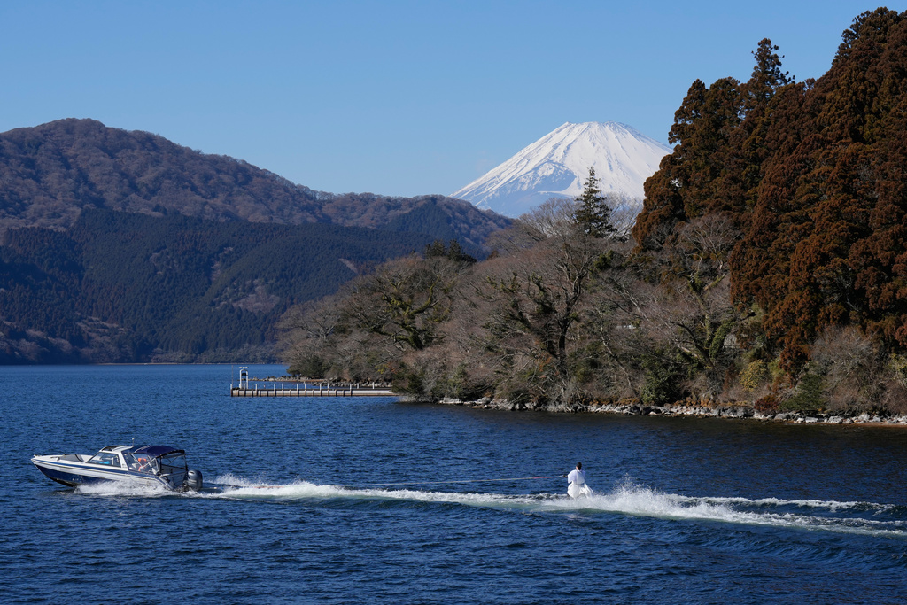 A student depicting a shrine priest skims across the water on water skis, with Mt. Fuji in the background, during the annual Bean Throwing Festival in Lake Ashi, near Hakone Shrine, Japan, Tuesday, Feb. 3, 2026. (AP Photo/Eugene Hoshiko)