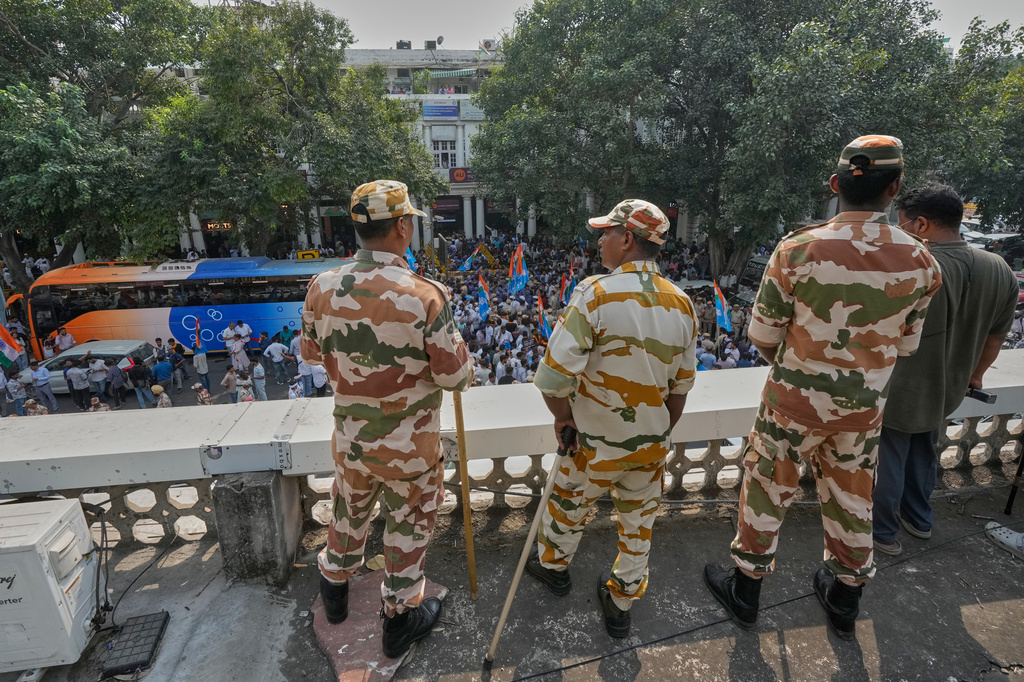 Security personnel keep vigil from the rooftop of a building as members of the student wing of India's Congress party and other protesters gather to start a march demanding the resignation of the country's election chief Gyanesh Kumar, in New Delhi, India, Thursday, Oct. 8, 2026. (AP Photo/Manish Swarup)