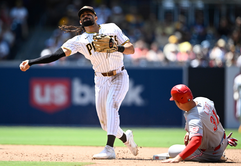 San Diego Padres second baseman Fernando Tatis Jr. throws past Cincinnati Reds' Nathaniel Lowe (31) as he tries to turn a double play during the sixth inning of a baseball game, Wednesday, June 10, 2026, in San Diego. (AP Photo/Denis Poroy)