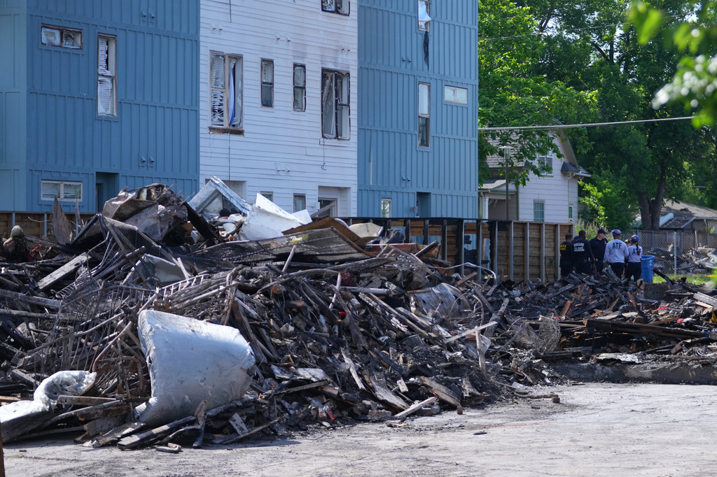 Officials stand near rubble following an apartment complex fire, Friday, May 29, 2026, in Dallas. (AP Photo/Julio Cortez)