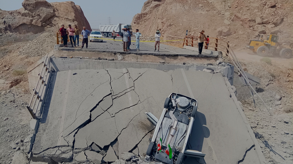 An overturned car sits on a section of a destroyed bridge after a strike in Hormozgan province, southern Iran, Saturday, July 18, 2026. (Mahdi Negahban/Mehr News Agency via AP)
