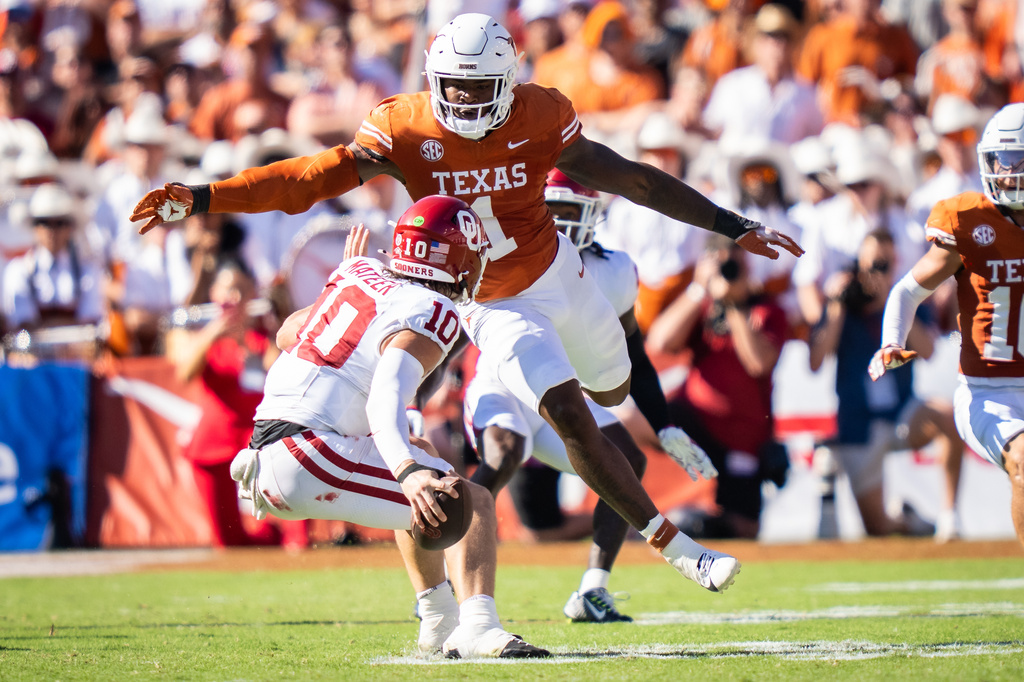 FILE - Texas linebacker Colin Simmons (1) goes to tackle Oklahoma Sooners quarterback John Mateer (10) during the second quarter of an NCAA college football game at the Cotton Bowl in Dallas, Oct. 11, 2025. (Sara Diggins/Austin American-Statesman via AP, File)