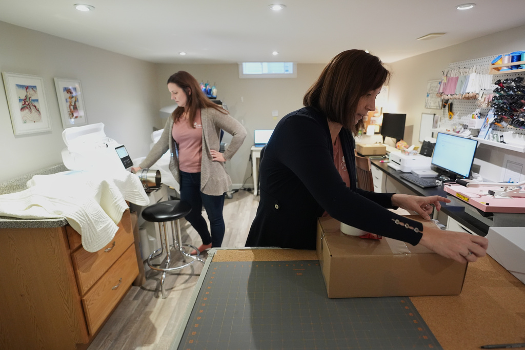 Fran Poirier, right, and her sister, Sue Bacarro, left, fill orders at their Etsy shop, Digi Wildflowers, Thursday, Oct. 30, 2025, in Windsor, Ontario, Canada. (AP Photo/Paul Sancya)