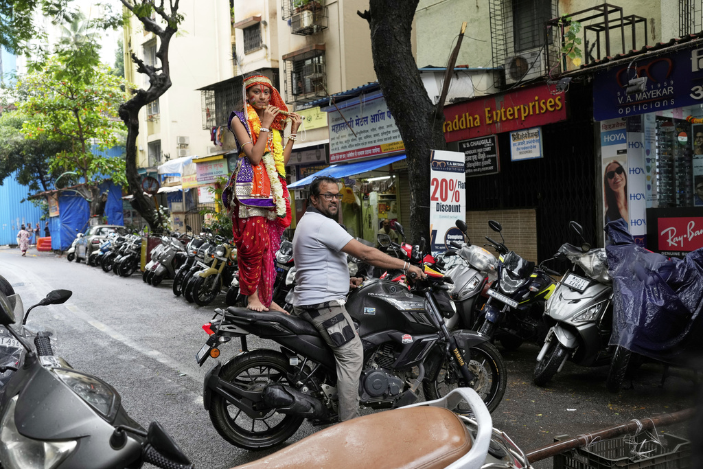 A girl dressed as Hindu deity Lord Krishna stands on a motorcycle during celebrations to mark Janmashtami festival in Mumbai, India, Saturday, Aug. 16, 2025. (AP Photo/Rajanish Kakade)