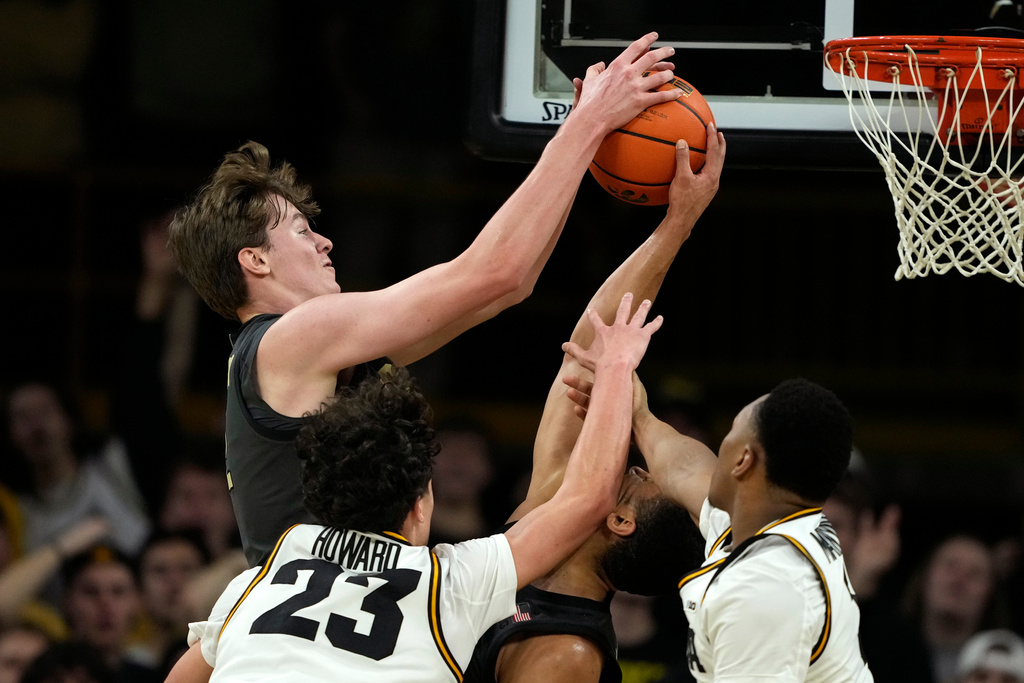 Purdue center Daniel Jacobsen, top left, grabs a rebound over Iowa guard Isaia Howard (23) during the first half of an NCAA college basketball game, Saturday, Feb. 14, 2026, in Iowa City, Iowa. (AP Photo/Charlie Neibergall)
