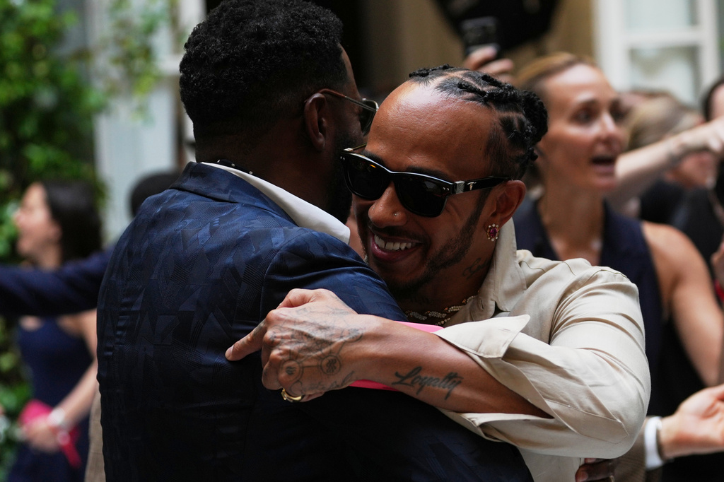 Lewis Hamilton, right hugs Colman Domingo as he arrives for the Ralph Lauren Spring/Summer 2027 men's collection, presented in Milan, Italy, Friday, June 19, 2026. (AP Photo/Antonio Calanni)