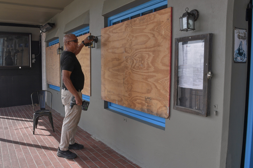 A man boards up his business' windows in preparation of Hurricane Imelda in Hamilton, Bermuda, Wednesday, Oct. 1, 2025. (AP Photo/Anthony Wade)