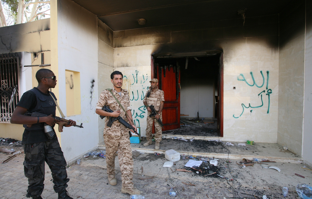 FILE - Libyan military guards check one of the U.S. Consulate's burnt-out buildings, Sept. 14, 2012, during a visit by Libyan President Mohammed el-Megarif, not pictured, to the U.S. Consulate to express sympathy for the death of American ambassador Chris Stevens and his colleagues after the deadly attack on the Consulate on Sept. 11, in Benghazi, Libya. (AP Photo/Mohammad Hannon, File)