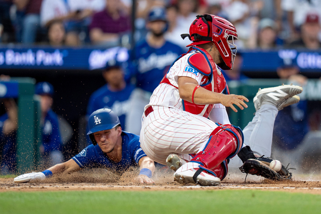 Los Angeles Dodgers' Tommy Edman, left, slides into home before Philadelphia Phillies catcher Rafael Marchan, right, could tag him during the fifth inning of a baseball game, Wednesday, July 22, 2026, in Philadelphia. (AP Photo/Chris Szagola)