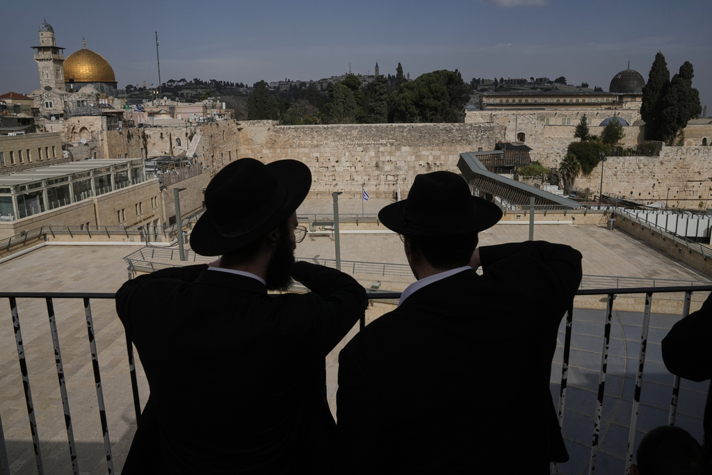 Ultra-Orthodox Jewish men stand near an empty Western Wall at Jerusalem's Old City, Thursday, March 19, 2026, as the area remains closed to visitors under nationwide Home Front Command restrictions banning large gatherings amid the war with Iran. (AP Photo/Mahmoud Illean)