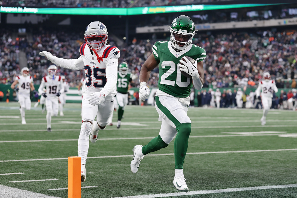 New York Jets running back Breece Hall (20) runs for a touchdown against New England Patriots cornerback Miles Battle (35) during the second half of an NFL football game, Sunday, Dec. 28, 2025, in East Rutherford, N.J. (AP Photo/Adam Hunger)