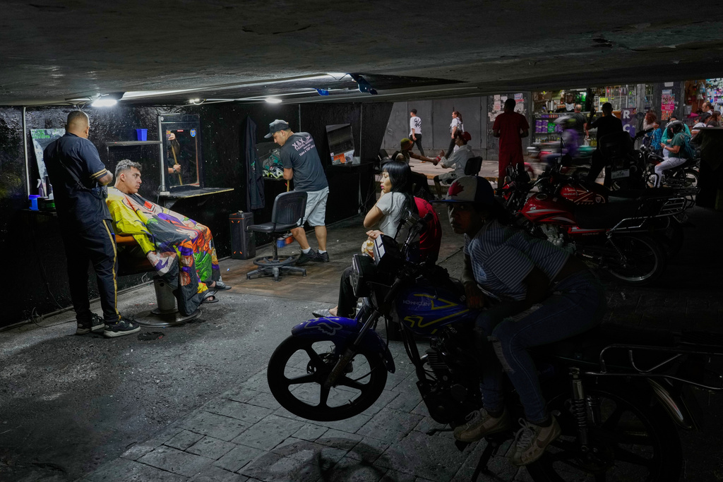 A man gets a haircut at a barbershop under the Fuerzas Armadas bridge in Caracas, Venezuela, Monday, Nov. 24, 2025. (AP Photo/Ariana Cubillos)