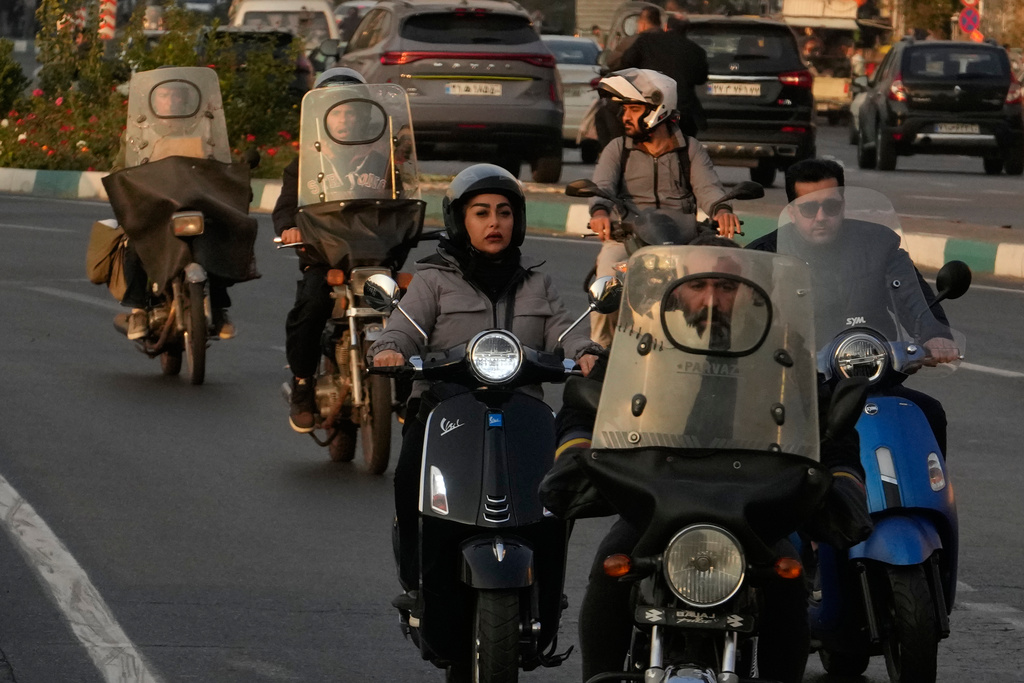 A woman drives her motorbike in downtown Tehran, Iran, Saturday, Nov. 8, 2025. (AP Photo/Vahid Salemi)