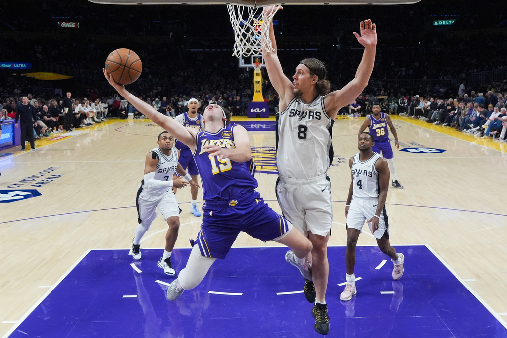 Los Angeles Lakers guard Austin Reaves (15) goes up for a basket under pressure by San Antonio Spurs forward Kelly Olynyk (8) during the first half of an NBA Cup basketball game Wednesday, Dec. 10, 2025, in Los Angeles. (AP Photo/Jae C. Hong)