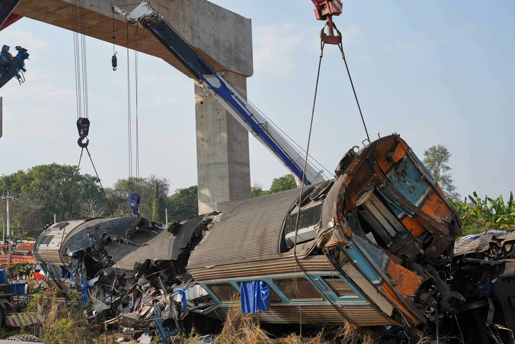 Rescuers try to lift the wreckage after a construction crane fell into a passenger train in Nakhon Ratchasima province, Thailand, Wednesday, Jan.14, 2026. (AP Photo/Sakchai Lalit))