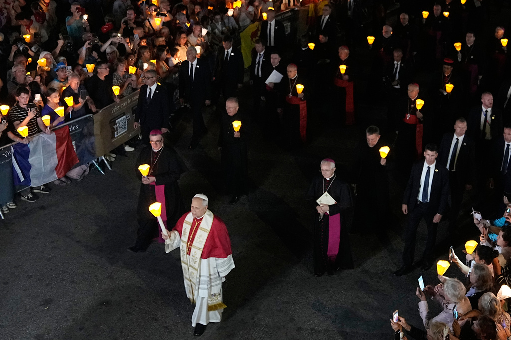 Pope Leo XIV, center, holds a candle during a prayer of Holy Rosary and torchlight procession at the Sanctuary of Our Lady of Lourdes, France, Sunday, Sept. 27, 2026. ((AP Photo/Laurent Cipriani)