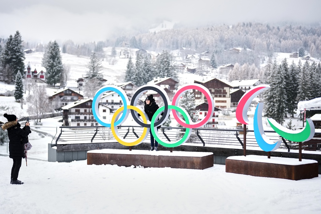 FILE - People take photos in front of the Milan Cortina Winter Olympics and Paralympics rings, in Cortina D'Ampezzo, Thursday, Nov. 20, 2025. (AP Photo/Andrew Medichini, File)