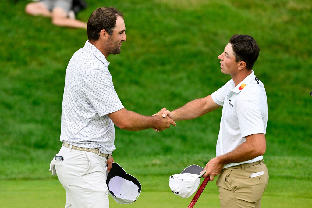 Scottie Scheffler, left, shakes hands with Viktor Hovland, right, of Norway, on the 18th green after finishing the third round of the Travelers Championship golf tournament at TPC River Highlands, Saturday, June 27, 2026, in Cromwell, Conn. (AP Photo/Jessica Hill)