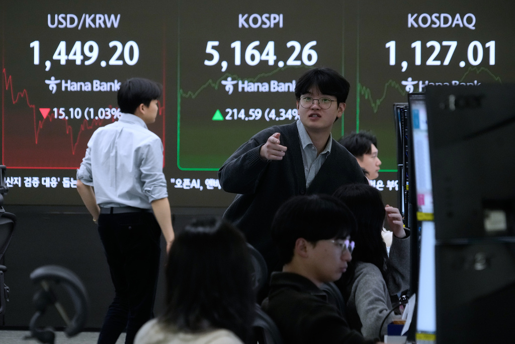 Currency traders work near a screen showing the Korea Composite Stock Price Index (KOSPI), top center, and the foreign exchange rate between U.S. dollar and South Korean won, top left, at the foreign exchange dealing room of the Hana Bank headquarters in Seoul, South Korea, Tuesday, Feb. 3, 2026. (AP Photo/Ahn Young-joon)
