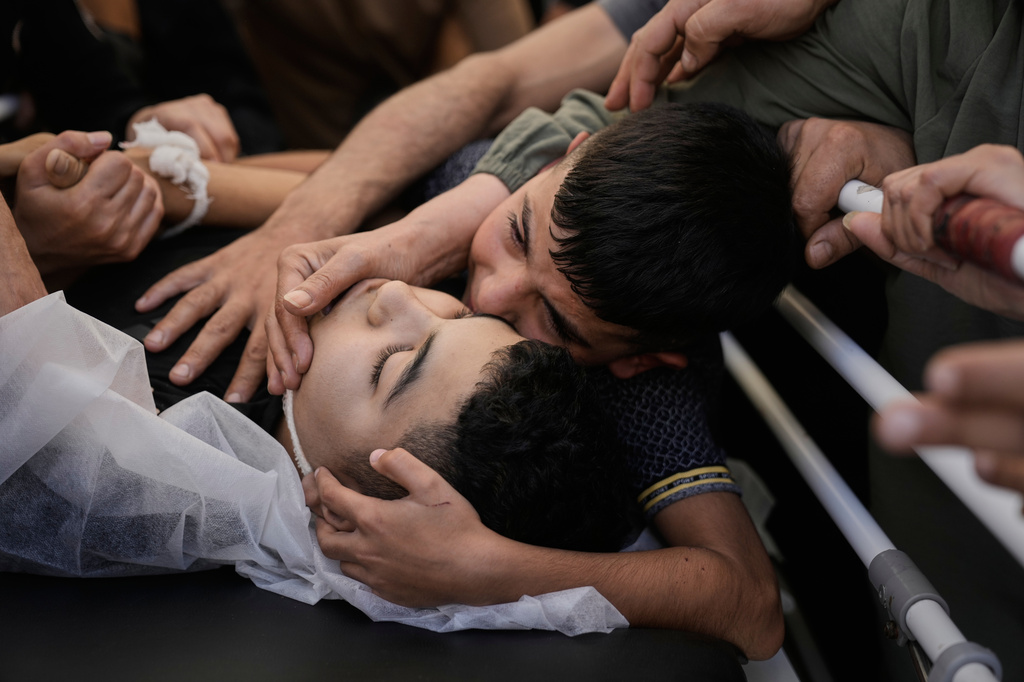 Mohammed Ajouri mourn over the body of his brother Islam Ajouri, 14, who, according to the Palestinian Ministry of Health, was killed by Israeli forces, as his body is brought to the hospital in the West Bank city of Nablus, Sunday, Aug. 23, 2026. (AP Photo/Majdi Mohammed)