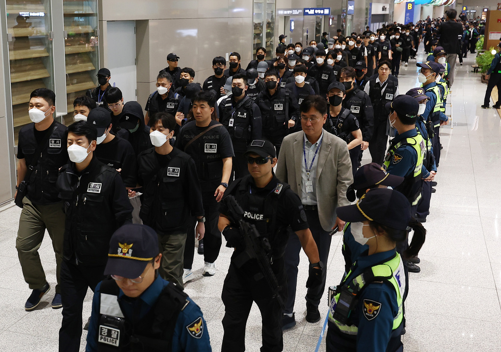 South Koreans, wearing caps, allegedly involved in online scams in Cambodia arrive at the Incheon International Airport, in Incheon, Saturday, Oct. 18, 2025. (Yonhap via AP)