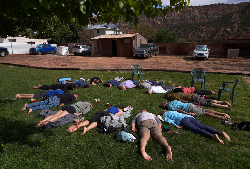 FILE - Participants lay face down on the grass during an integration circle at an ayahuasca retreat in Hildale, Utah, Oct. 15, 2022. (AP Photo/Jessie Wardarski, File)