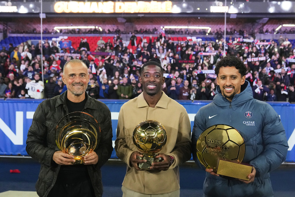 PSG's head coach Luis Enrique holds the 2025 Johann Cruyff trophy for the best coach of the year, Ousmane Dembele the Men's Ballon d'Or, or Golden Ball, for the best player of the year and team captain Marquinhos, right, the Club of the Year award that were awarded earlier in the week, after the French League One soccer match between Paris Saint-Germain and Auxerre at the Parc des Princes in Paris, Saturday, Sept. 27, 2025. (AP Photo/Thibault Camus)