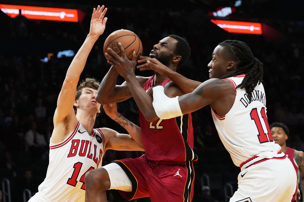 Miami Heat forward Andrew Wiggins (22) drives to the basket as Chicago Bulls forward Matas Buzelis (14) and guard Ayo Dosunmu (11) defend during the first half of an NBA basketball game, Saturday, Jan. 31, 2026, in Miami. (AP Photo/Lynne Sladky)