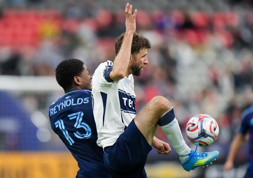 Vancouver Whitecaps' Thomas Muller, front right, and Sporting Kansas City's Justin Reynolds vie for the ball during the first half of an MLS soccer match, in Vancouver, on Friday, April 17, 2026. (Darryl Dyck/The Canadian Press via AP)