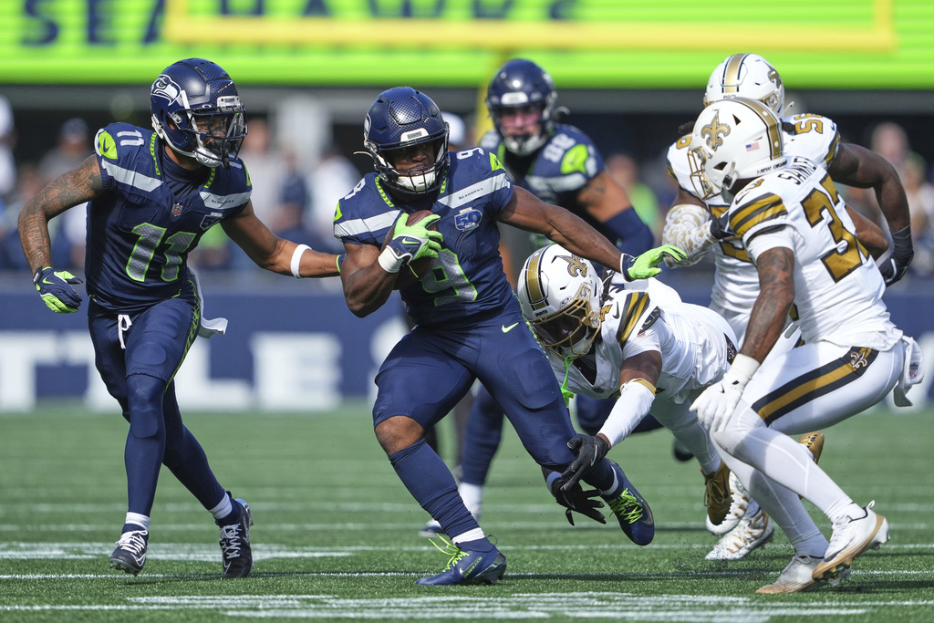 Seattle Seahawks running back Kenneth Walker III (9) carries against New Orleans Saints cornerback Kool-Aid McKinstry (4) ad safety Jonas Sanker (33) during the first half of an NFL football game, Sunday, Sept. 21, 2025, in Seattle. (AP Photo/Lindsey Wasson)