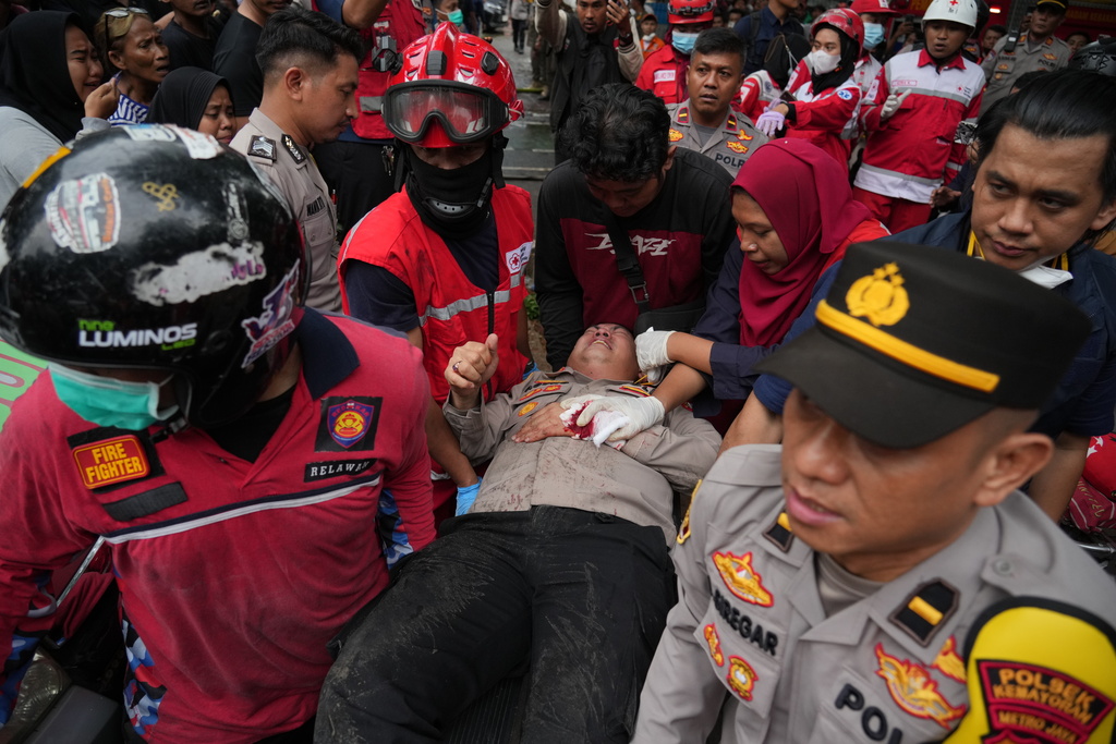 Rescuers tend to an injured police officer at the site of a fire in Jakarta, Indonesia, Tuesday, Dec. 9, 2025. (AP Photo/Dita Alangkara)