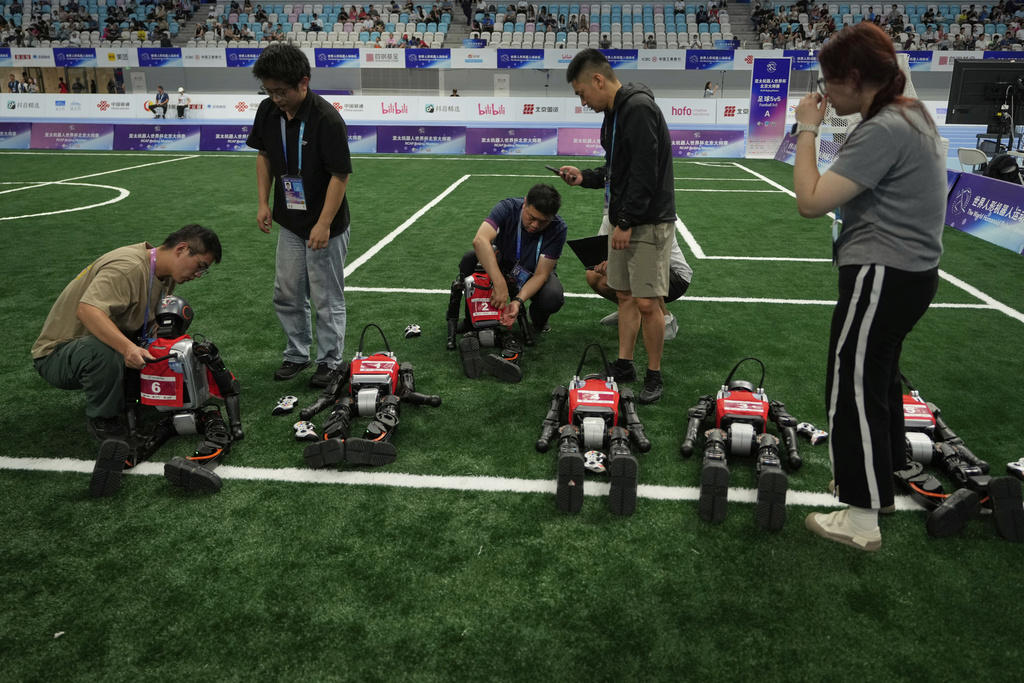 Technicians work on robots before a soccer game at the World Humanoid Robot Games held in Beijing, China, Friday, Aug. 15, 2025. (AP Photo/Mahesh Kumar A.)