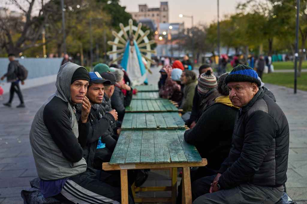 Men wait to receive free food after attending a Mass organized by the Catholic Church at a square outside the Constitución train station in Buenos Aires, Argentina, Tuesday, Sept. 22, 2026. (AP Photo/Rodrigo Abd)